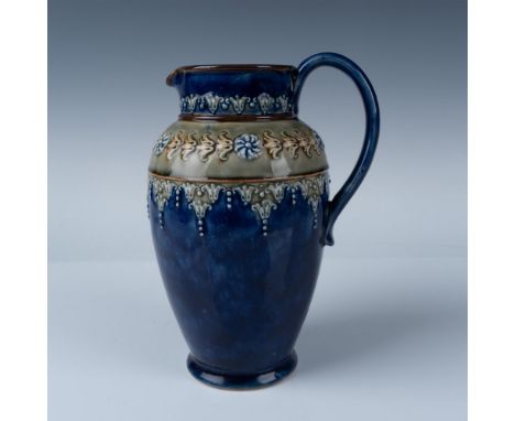 A blue round pitcher with a green ring at the top of its body, decorated with low relief art of flowers and foliage patterns.