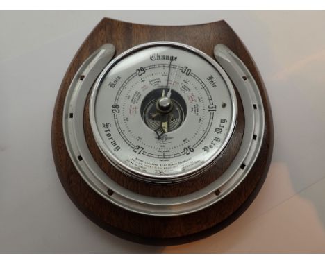 Wall hanging barometer surrounded by brass horse shoe