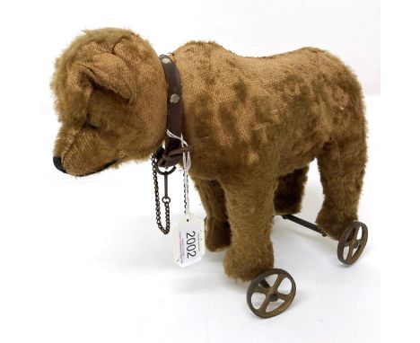 An Early 20th Century Steiff Pull Along Bear on Wheels, with jointed head, boot button eyes, stitched nose, brown leather stu