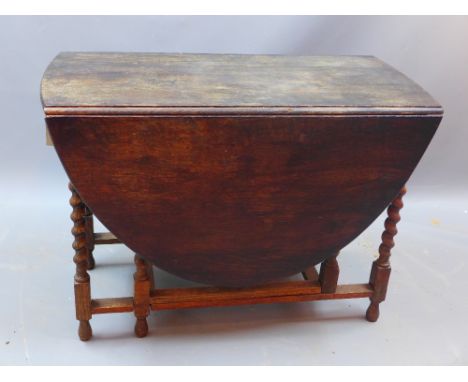A 20th century oak drop leaf gate leg table raised on barley twist supports on bun feet H 73 x W 148 x D 104cm 