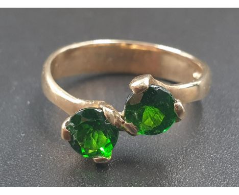 A 9CT GOLD CROSSOVER RING WITH 2 GREEN STONES.3.0gms AND SIZE L 