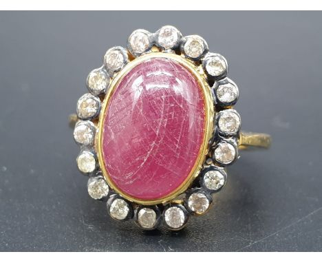A cabochon ruby gemstone ring with a halo of white diamond accents approx .40cents size O 