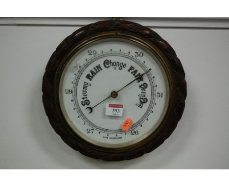 An early 20th century aneroid barometer in circular carved oak surround