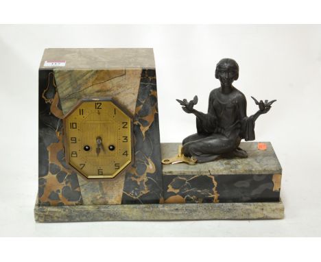 An Art Deco marble cased mantel clock, having a brass dial with Arabic numerals, surmounted by a kneeling female and birds