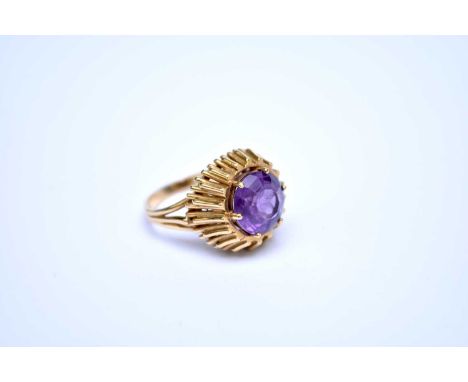 A single stone amethyst ring, the round mixed cut amethyst claw set in yellow metal to raised decorative mount, the yellow me