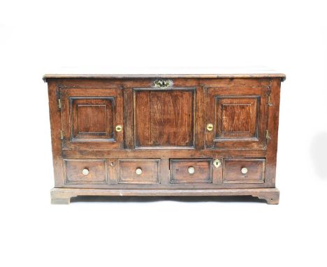 An 18th century oak mule chest, the moulded top above a panelled front with two cupboard doors above two moulded drawers, rai