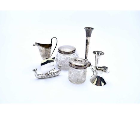 A small collection of silver, comprising; a helmet cream jug, two silver topped glass dressing table jars, a miniature trophy