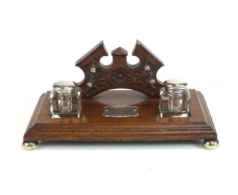 An Edwardian silver mounted oak desk stand, of rectangular outline with moulded edge and raised on silver bun feet, with a ca