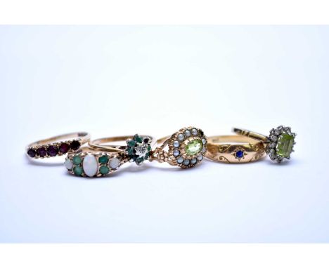 A collection of five 9ct gold stone set rings, comprising; a peridot and seed pearl oval cluster, a seven stone opal and emer