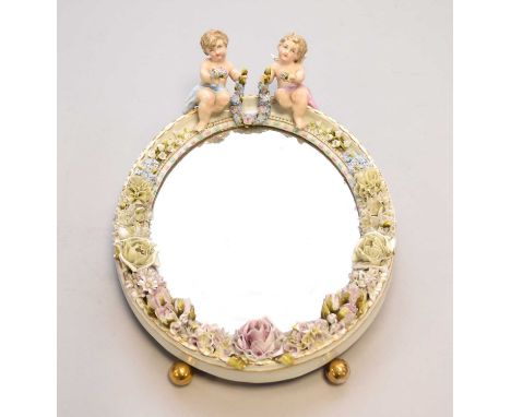 A 19th century Dresden easel mirror, with a floral encrusted frame and surmounted by two winged putti, losses and damaged, 38