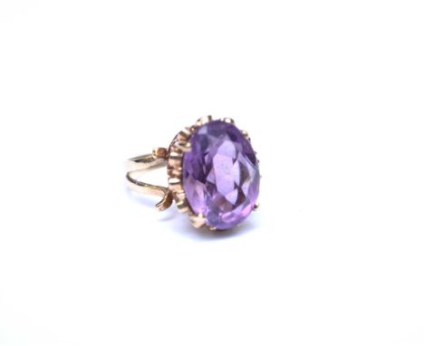 A 9ct gold single stone amethyst ring, designed as a central oval mixed cut amethyst claw set in yellow gold to raised pierce