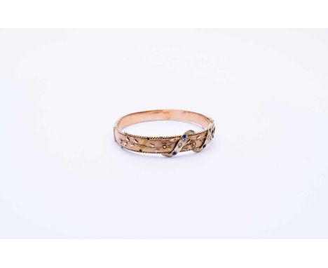 A diamond and blue paste bangle, designed as two stone set scrolls mounted to yellow metal bangle with applied flower and lea