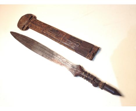 A 19th Century Yaka shortsword with lether scabbard, length 64cm.