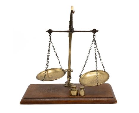 Steel and brass pharmacy scales and two weights. Wooden base W 32cm, D 16cm, total height 31cm.