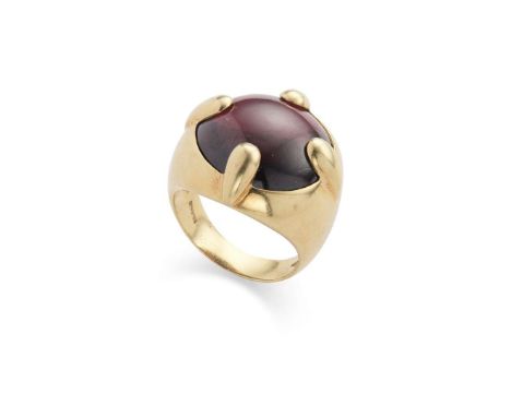  A garnet dress ring  Claw-set with a cabochon garnet, to a bold mount with plain band, stamped 750 Ring size: J   