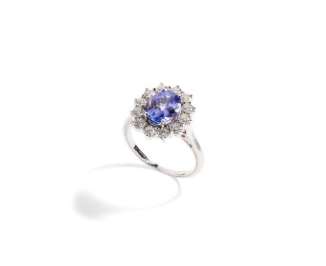  A Tanzanite and diamond cluster ring  Claw-set with an oval-cut Tanzanite in a border of twelve round brilliant-cut diamonds