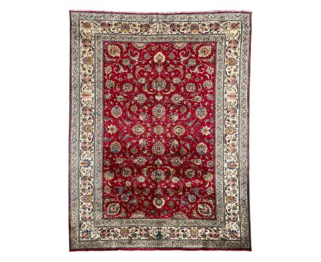 Persian Tabriz crimson ground carpet, decorated with swirling leafy branches and large palmette motifs, the pale ground borde