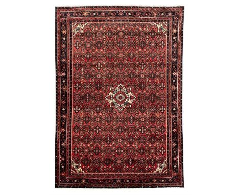Persian Heratti crimson ground rug, the field decorated with repeating floral Heratti motifs, ivory ground central medallion 