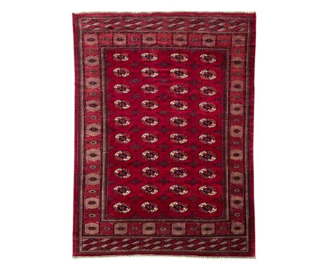 Afghan Bokhara red ground carpet, the field decorated with four rows of Gul motifs interspersed with Hac motifs, the border w
