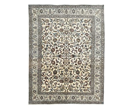 Persian Kashan ivory ground carpet, the field decorated with trailing leafy branches and palmette motifs, scrolling border in