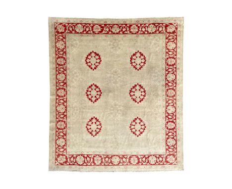 Persian Ziegler pale wheat and crimson ground carpet, the field decorated with floral medallions and faint pattern outlines, 