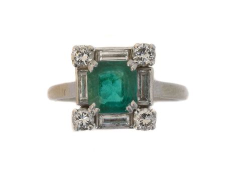 A platinum emerald and diamond cluster ring by Mauboussin. The emerald cut emerald weighing approx. 1.30cts within a brillian