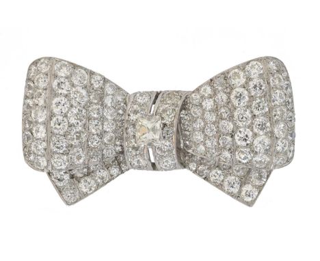 An early 20th century French diamond bow brooch. Set with a principal cushion cut diamond weighing approx. 0.55ct atop a vari