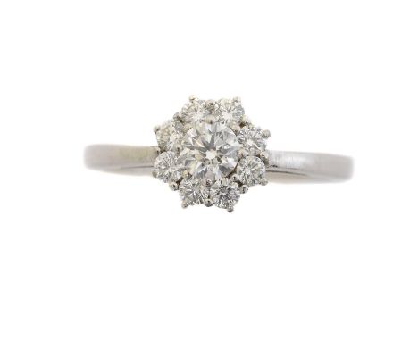 An 18ct gold diamond cluster ring. The brilliant cut diamond within a similarly cut diamond surround, estimated total diamond