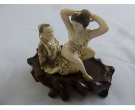 Japanese late 19th century erotic two part Netsuke on hardwood stand, 9cm (h) incl. stand