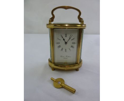 Charles Frodsham of London brass carriage clock, shaped oval, white enamel dial with Roman numerals to include key