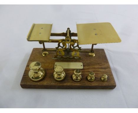 A set of brass postal scales with brass weights on rectangular wooden base
