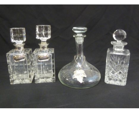 A pair of square cut glass decanters with silver collars and silver brandy and whisky labels and a ships decanter with silver