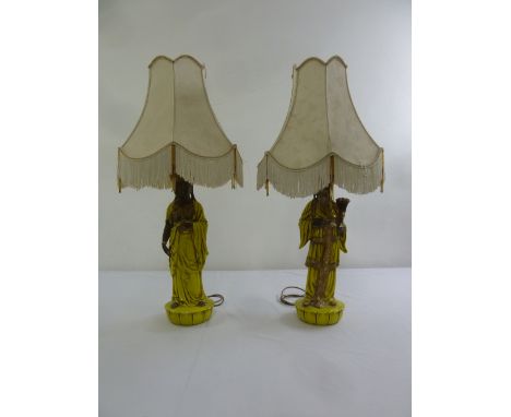 A pair of Oriental ceramic table lamps in the form of a male and female on raised circular bases to include shades