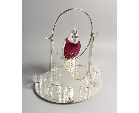 AN UNUSUAL LIQUEUR SET, the decanter modelled as a parrot on a swing, with six shot glasses to the oval base. 16ins high.