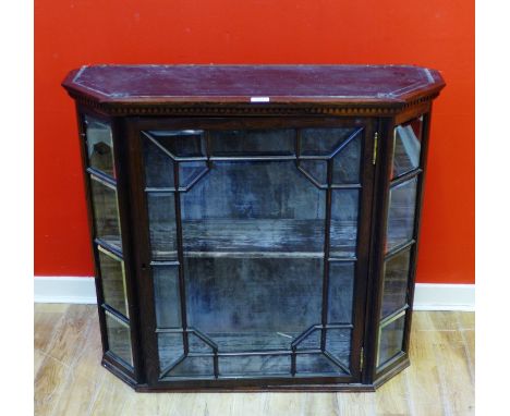 An Edwardian rosewood display cabinet with dentil  moulding to top above glazed panel door, enclosing lined interior with a f