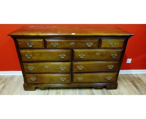 A contemporary mahogany chest of drawers having a moulded top above central long drawer flanked by two short over two banks o