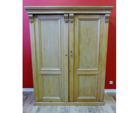 A 19th century pine two door wardrobe with moulded cornice to top above two panel doors enclosing a fitted interior and raise