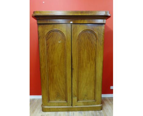 A Victorian mahogany two door wardrobe having a moulded cornice to top above two panel doors enclosing a fitted interior and 