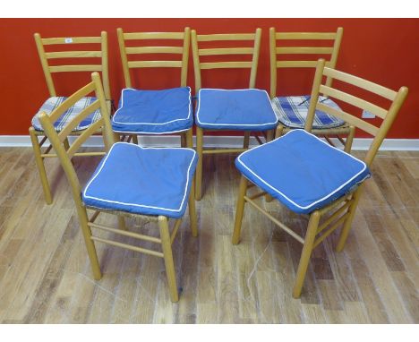 A set of ladder back beech dining chairs, having ropework seats raised on turned supports and stretchers. 