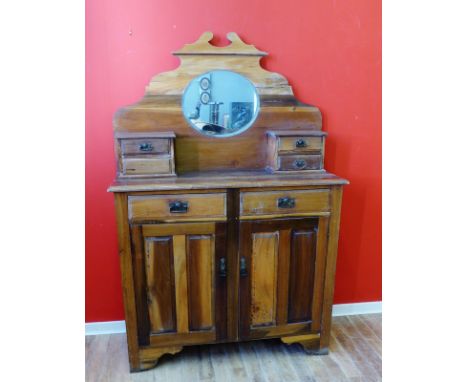 A late Victorian pine mirror backed cabinet with the mirror back being flanked by four short drawers above a moulded top, two