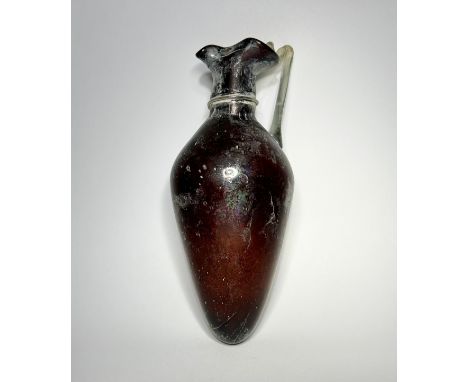 Roman blown glass amphora type jug. Circa 1st-2nd century CE. 18 cm. A Translucent purple vessel with applied clear glass han