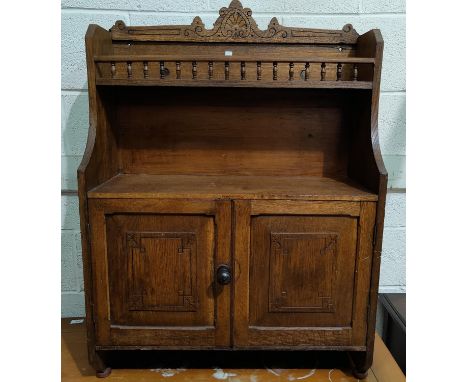 An Edwardian oak wall cabinet with double cupboard and galleried shelf under 