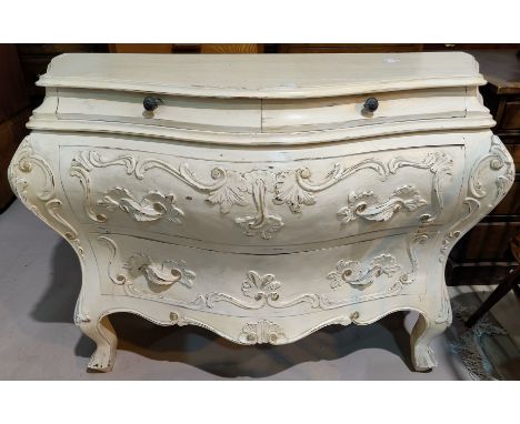 An early 20th century Italian bombe commode of 2 long and 2 short drawers, with carved decoration, on cabriole legs, in cream