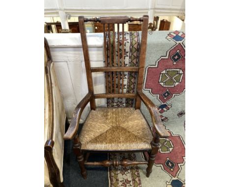 An oak rail back elbow chair with rush seat on turned legs and stretchers and a Victorian button upholstered chair with green