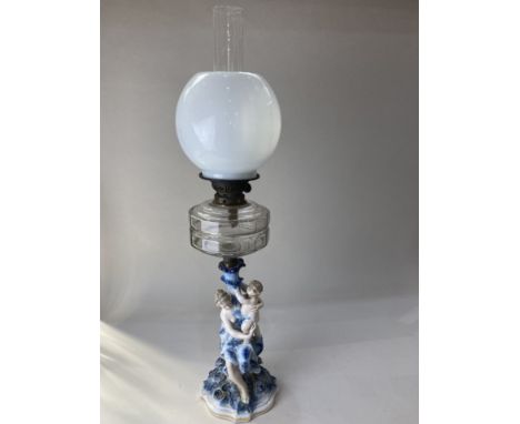 A blue and white porcelain figural oil lamp, with white glass shade and clear glass well, the base modelled with a mother and