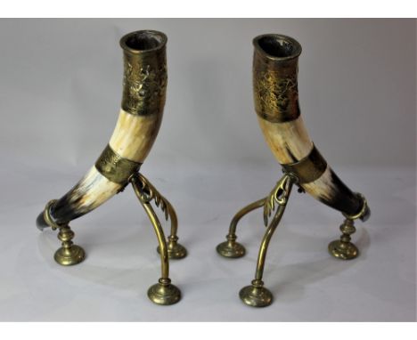 A pair of brass mounted cow horn vases, on tripod feet, 32cm high