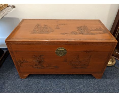 A Chinese carved camphor wood blanket chest, decorated with sailing ships and figural scenes, on bracket feet, 103.5cm