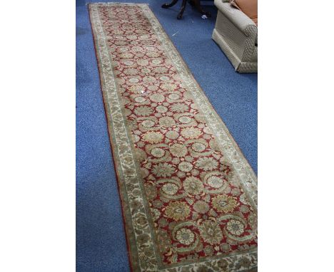 AN OLIVE GREEN AND RED GROUND CARPET RUNNER, 100% wool pile, hand knotted in India, approximate size 445cm X 93cm, G H Frith 