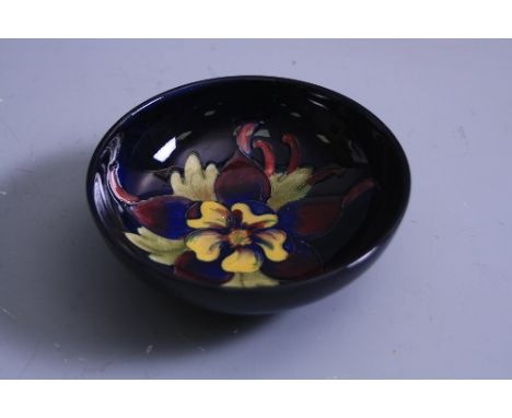 A MOORCROFT POTTERY FOOTED TRINKET DISH, Columbine pattern on blue ground, paper label to base, diameter approximately 11.5cm