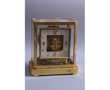 A JAEGER LE COULTRE ATMOS MANTLE CLOCK, in fitted case, with clear glass top and side panels, angled corners and square dial,